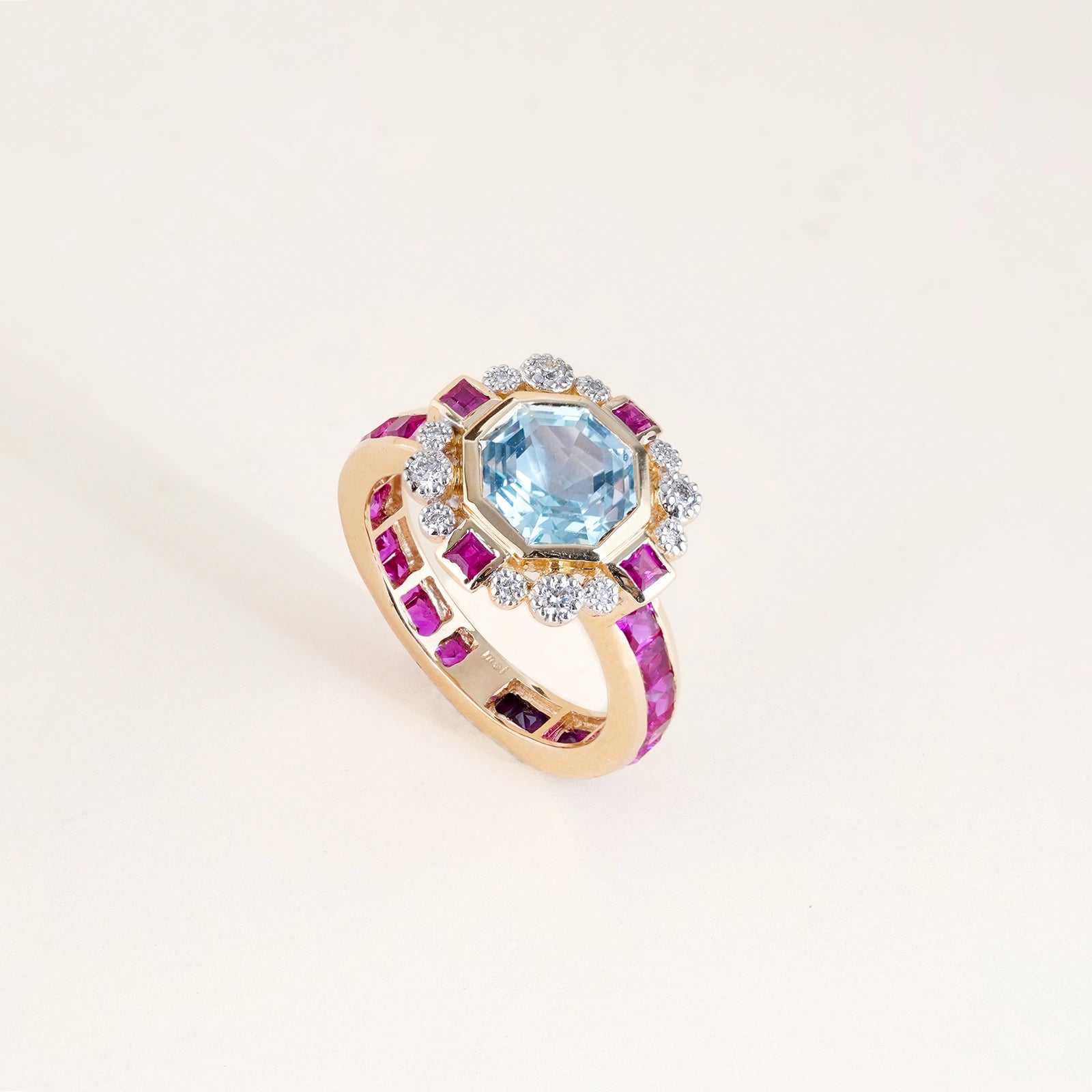 Elina Ring in 14K gold with custom-cut blue topaz in an Art Deco frame with claw-set diamonds, bazel-set rubies and channel-set topaz