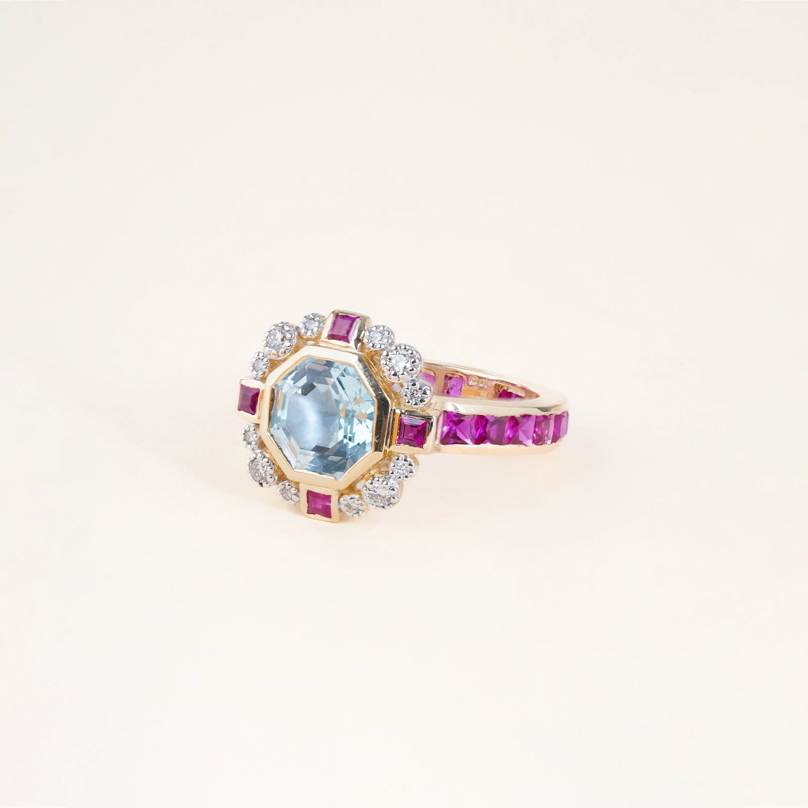 Elina Ring in 14K gold with custom-cut blue topaz in an Art Deco frame with claw-set diamonds, bazel-set rubies and channel-set topaz