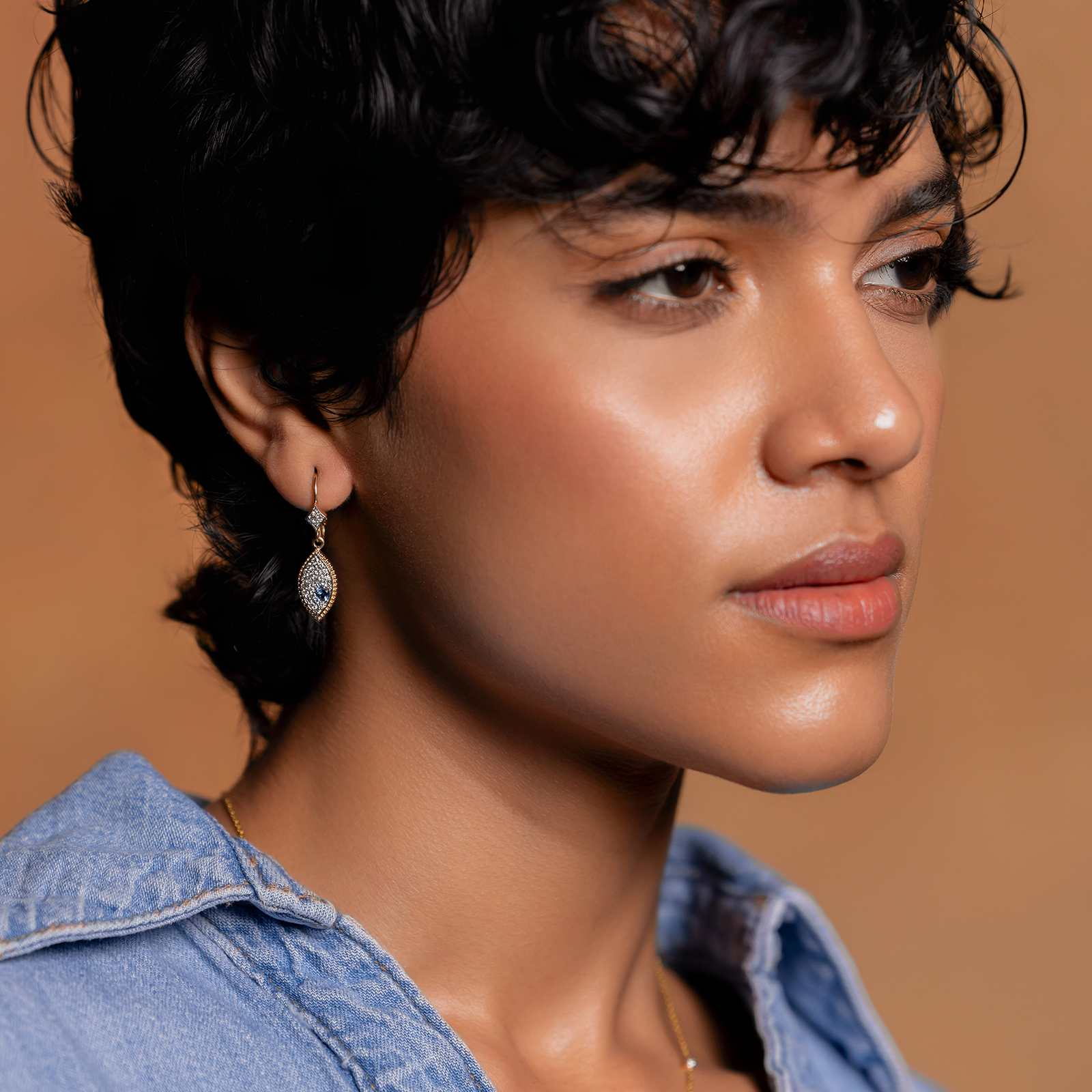 Evil Eye Earrings in 14K gold huggie hoops with blue topaz evil eye and natural brilliant-cut diamonds