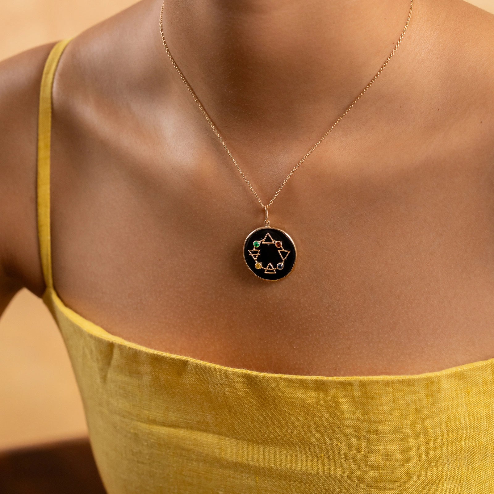 Maya Elements of Life Pendant in 14K gold with emerald, hessonite, yellow sapphire and blue sapphire on a black onyx base with coloured enamel