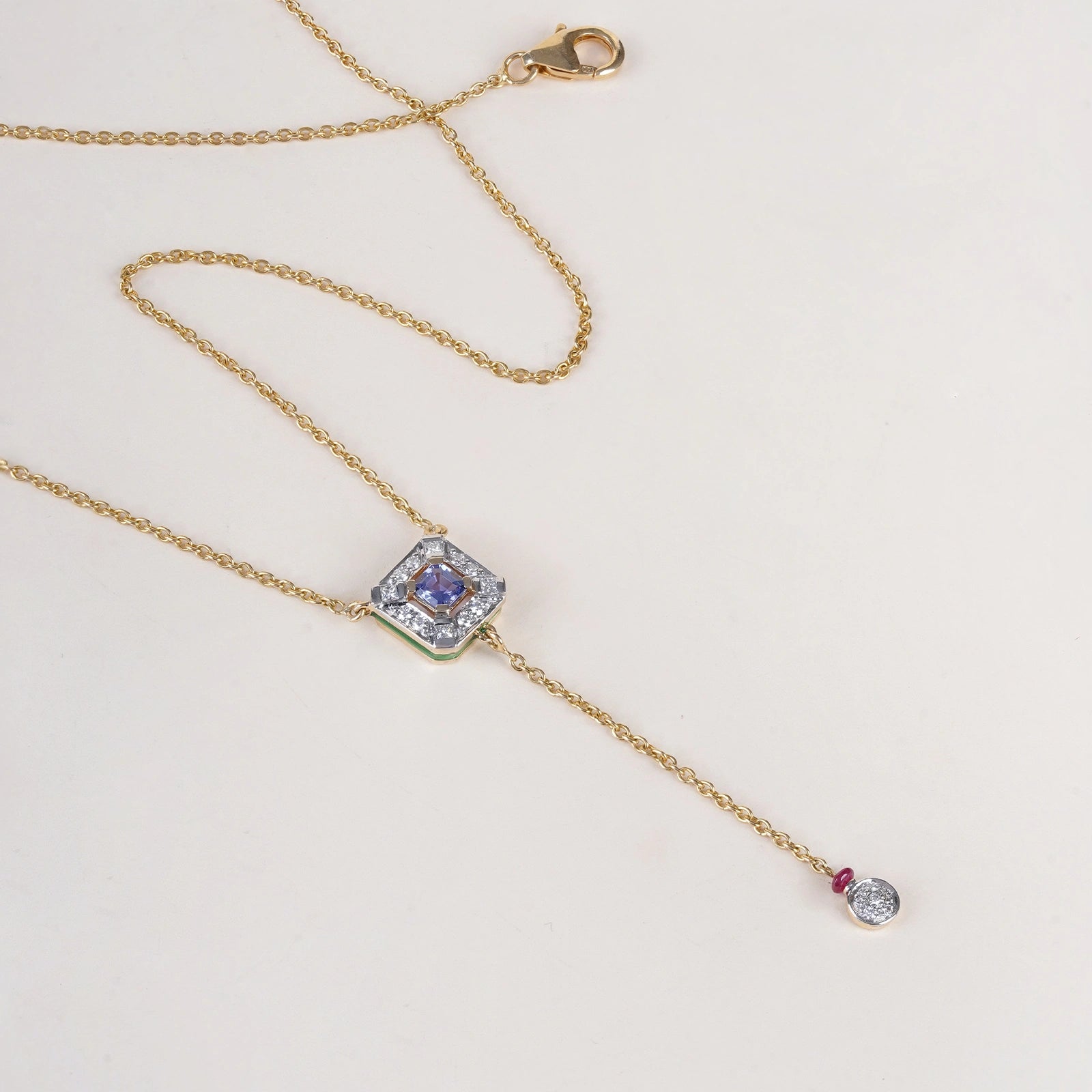 Nizam Tanzanite Pendant Necklace handcrafted in gold featuring a central tanzanite, brilliant and princess cut diamonds, green enamel detailing, and delicate dangling accents inspired by Indian artistry.