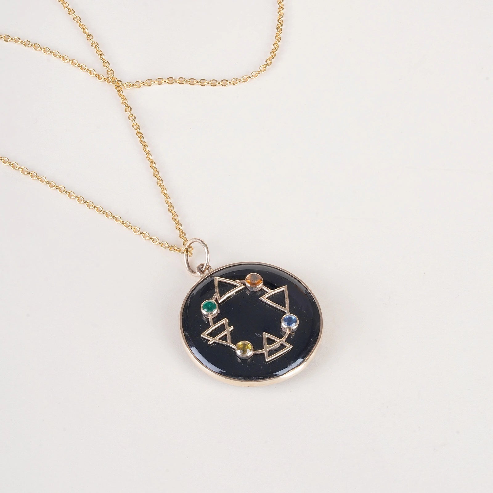 Maya Elements of Life Pendant in 14K gold with emerald, hessonite, yellow sapphire and blue sapphire on a black onyx base with coloured enamel
