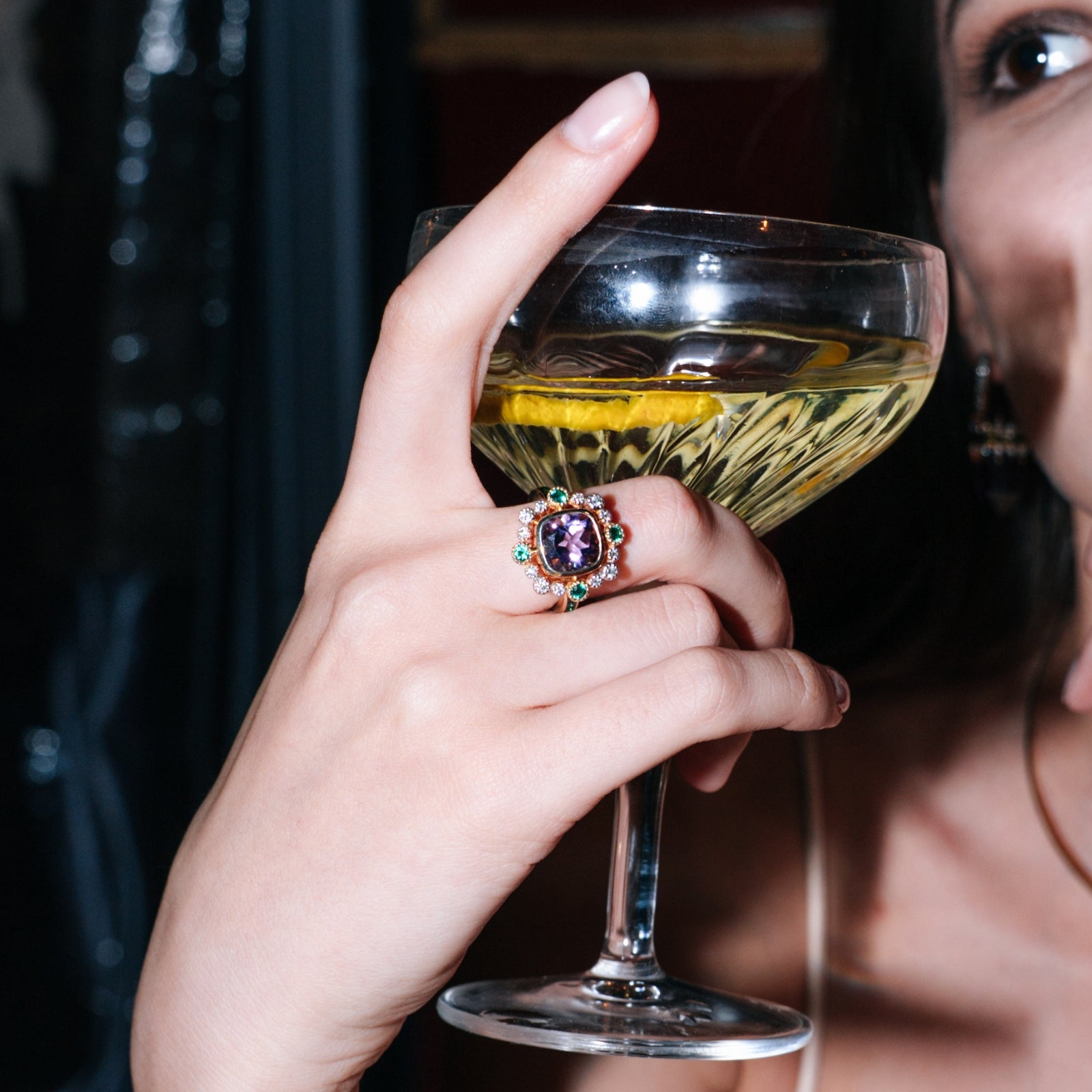 Close-up of the faceted amethyst center within its pave diamond and emerald halo