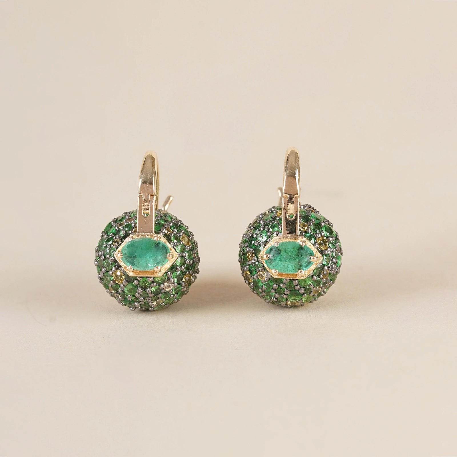Forest-inspired earrings with pavé tsavorite, yellow sapphire, and emerald, featuring a central emerald set in gold.