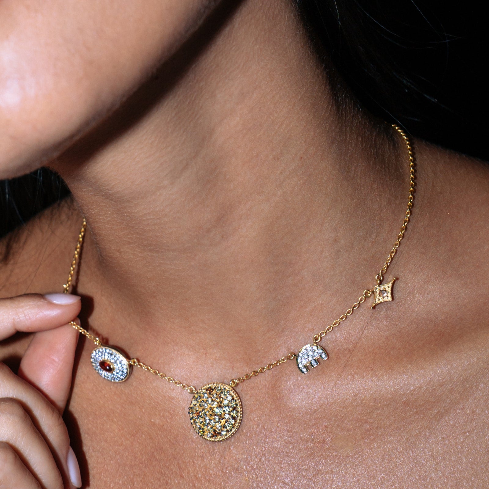Model wearing a sapphire charm necklace with a crisp white shirt